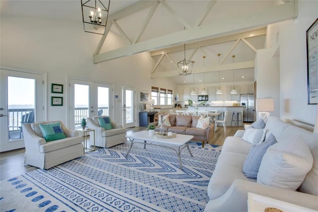 living room with beam ceiling, french doors, high vaulted ceiling, an inviting chandelier, and hardwood / wood-style floors