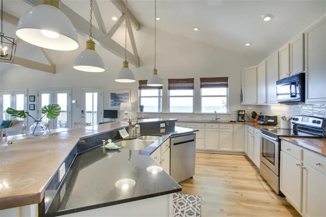 kitchen with a large island, white cabinets, appliances with stainless steel finishes, and a healthy amount of sunlight