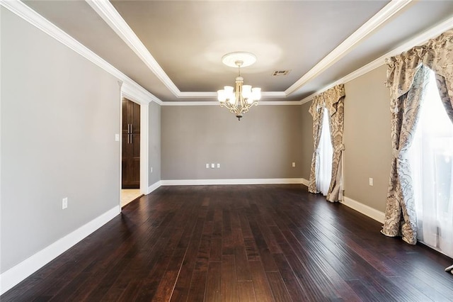 empty room with a chandelier, ornamental molding, dark hardwood / wood-style floors, and a raised ceiling