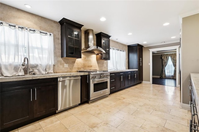 kitchen featuring appliances with stainless steel finishes, sink, decorative backsplash, light stone countertops, and wall chimney exhaust hood