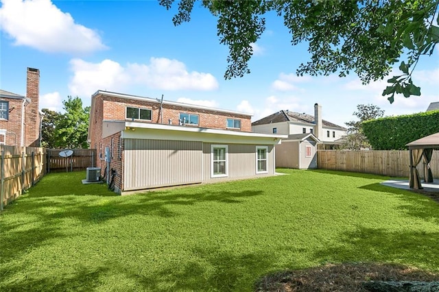 back of property featuring a storage shed, a lawn, and central air condition unit