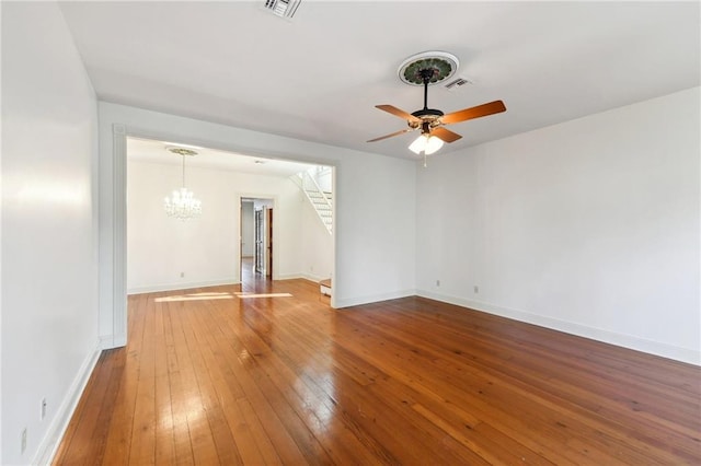 empty room featuring ceiling fan with notable chandelier and wood-type flooring