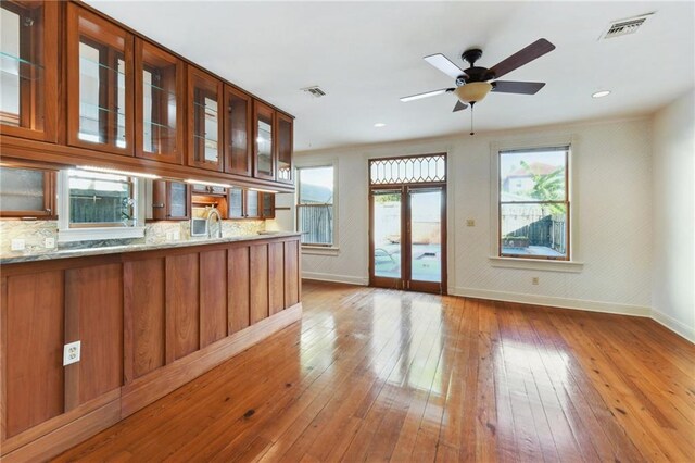 kitchen with light stone counters, sink, hardwood / wood-style flooring, stainless steel appliances, and decorative backsplash