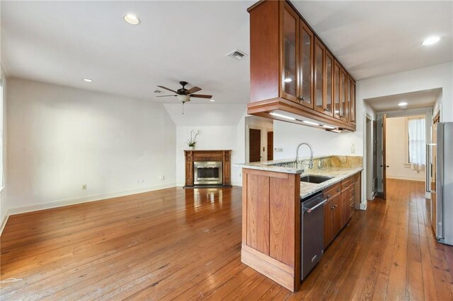 kitchen with sink, appliances with stainless steel finishes, dark hardwood / wood-style floors, light stone countertops, and decorative backsplash