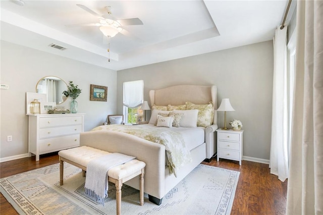 bedroom featuring a tray ceiling, dark hardwood / wood-style flooring, and ceiling fan