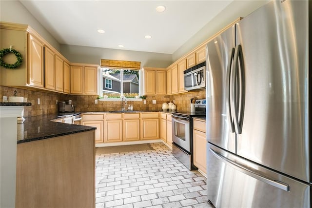 kitchen featuring dark stone counters, sink, backsplash, light brown cabinets, and appliances with stainless steel finishes