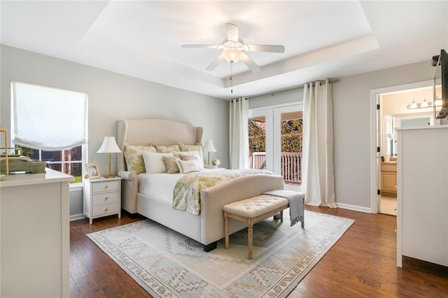 bedroom featuring multiple windows, a raised ceiling, ceiling fan, and dark hardwood / wood-style flooring