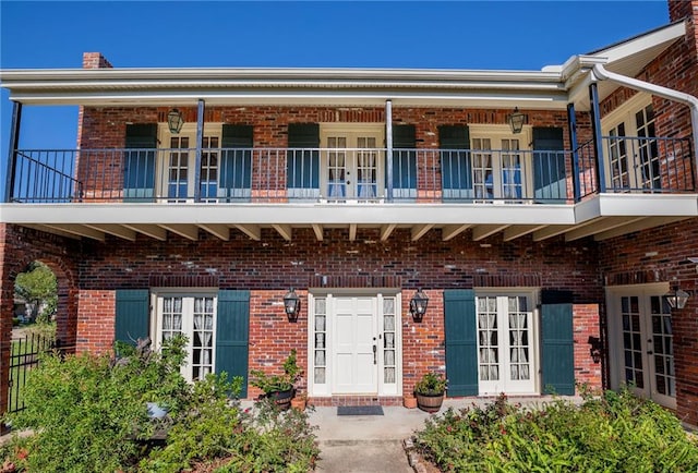 view of front of home featuring a balcony and french doors