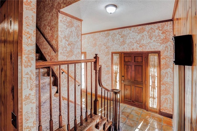 entrance foyer featuring a textured ceiling and ornamental molding