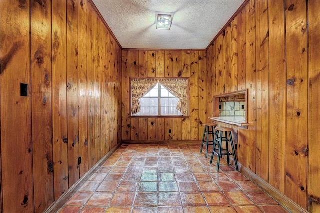 interior space featuring ornamental molding, wood walls, and a textured ceiling