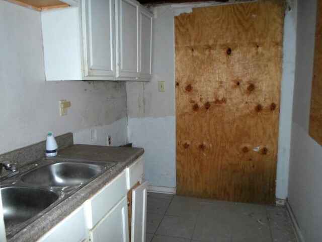 kitchen featuring white cabinets, light tile patterned flooring, and sink