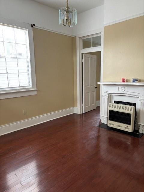 unfurnished living room featuring dark hardwood / wood-style floors, a chandelier, and heating unit