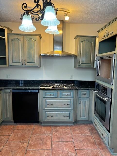 kitchen featuring hanging light fixtures, appliances with stainless steel finishes, a textured ceiling, gray cabinetry, and wall chimney exhaust hood