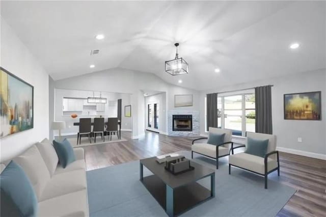 living room featuring a chandelier, a fireplace, wood-type flooring, and vaulted ceiling