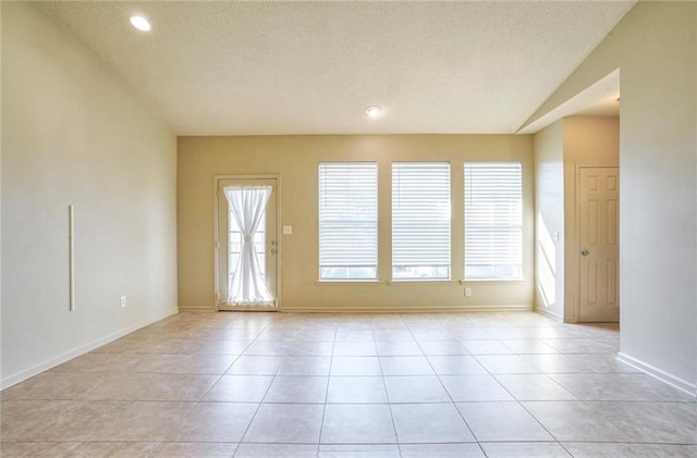 unfurnished room featuring light tile patterned flooring, plenty of natural light, and a textured ceiling