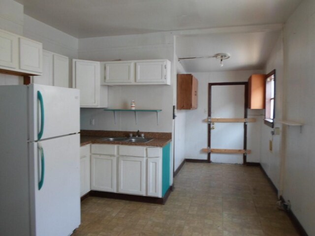 kitchen with white cabinetry, white refrigerator, and sink