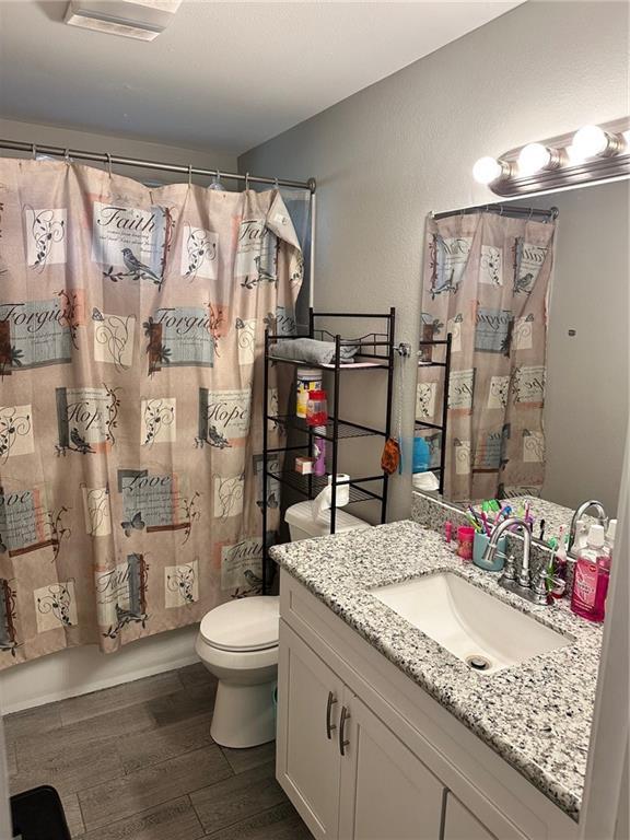 full bathroom featuring vanity, wood-type flooring, shower / tub combo, and toilet