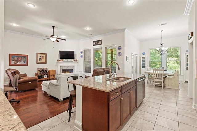 640 Pine Grove Loop, Madisonville, LA 70447 - kitchen featuring light tile patterned floors, stainless steel dishwasher, a lit fireplace, a kitchen breakfast bar, and crown molding