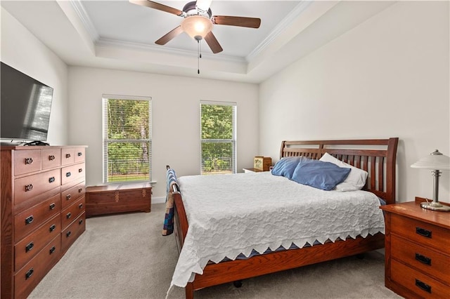 carpeted bedroom featuring crown molding, multiple windows, ceiling fan, and a tray ceiling