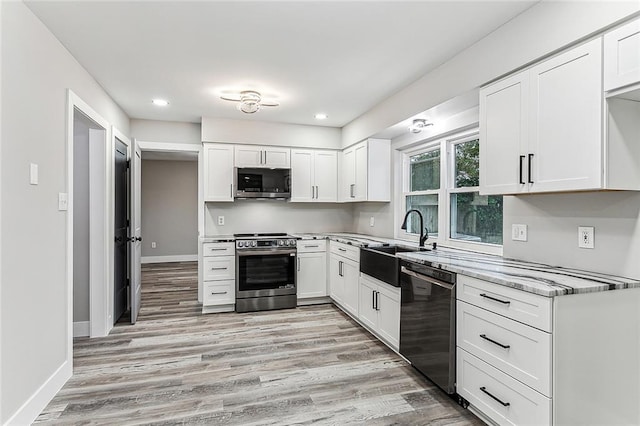 kitchen featuring appliances with stainless steel finishes, light wood-type flooring, white cabinetry, and sink