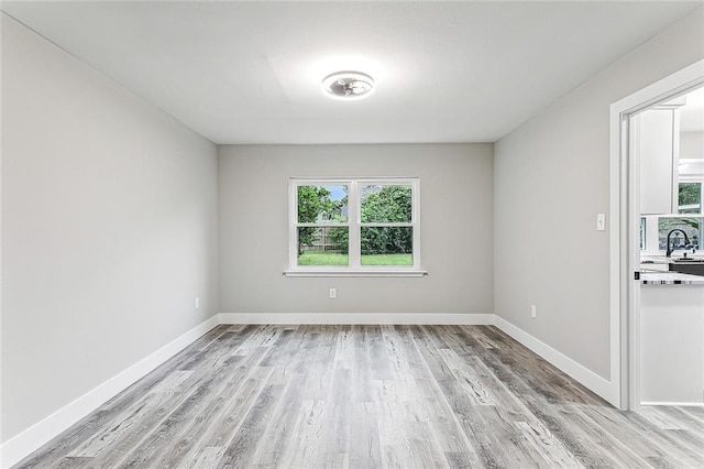 unfurnished room with sink and light hardwood / wood-style floors