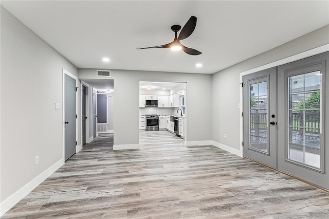 unfurnished living room with french doors, sink, light hardwood / wood-style floors, and ceiling fan