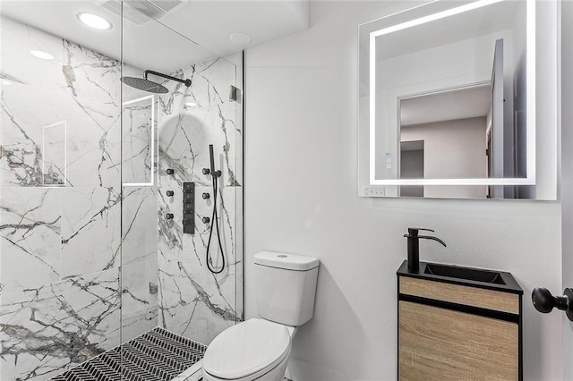 bathroom with vanity, toilet, and tiled shower