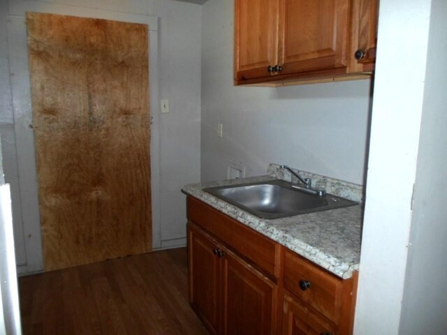 kitchen with light stone counters, dark hardwood / wood-style floors, and sink