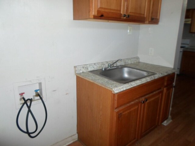 kitchen with light stone countertops, sink, and dark wood-type flooring