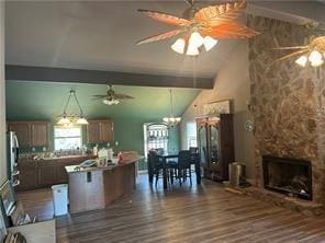 kitchen featuring a center island, a stone fireplace, dark hardwood / wood-style flooring, lofted ceiling, and a breakfast bar