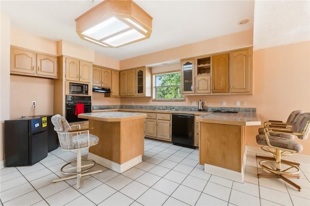 kitchen featuring black appliances, light tile patterned floors, a kitchen bar, and a kitchen island