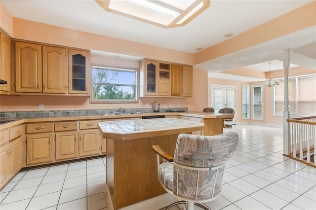 kitchen with light tile patterned flooring, tile counters, a center island, and a breakfast bar