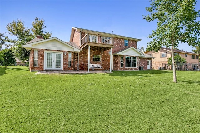 back of house with french doors, a balcony, and a lawn