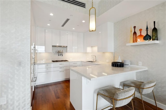 kitchen with a kitchen breakfast bar, dark hardwood / wood-style flooring, white cabinets, and decorative light fixtures