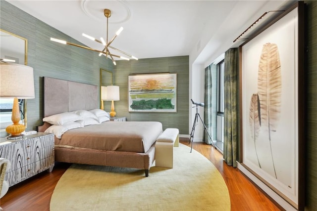 bedroom with wood-type flooring and an inviting chandelier