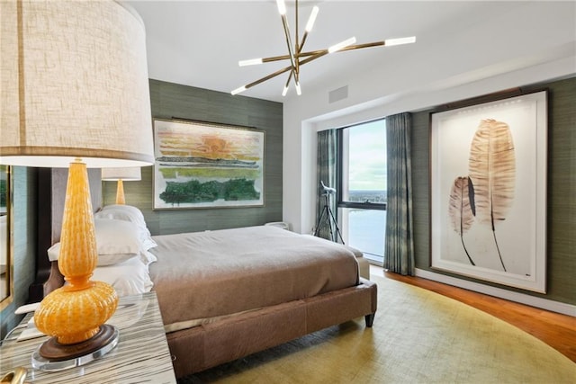 bedroom featuring access to outside, hardwood / wood-style floors, a water view, and a chandelier