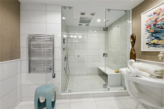 bathroom with tile patterned floors, a shower with shower door, radiator heating unit, and tile walls