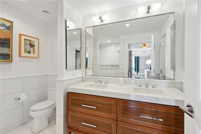 bathroom with vanity, a shower, tile walls, tile patterned flooring, and toilet