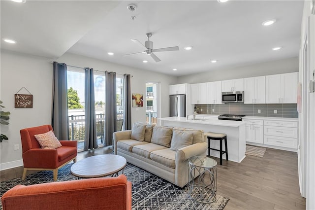 living room featuring ceiling fan, light hardwood / wood-style flooring, and sink