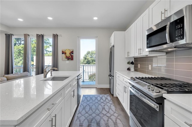 kitchen with dark wood-type flooring, sink, light stone counters, stainless steel appliances, and white cabinetry