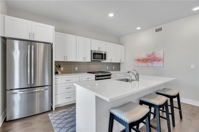 kitchen featuring appliances with stainless steel finishes, sink, white cabinetry, and a center island with sink