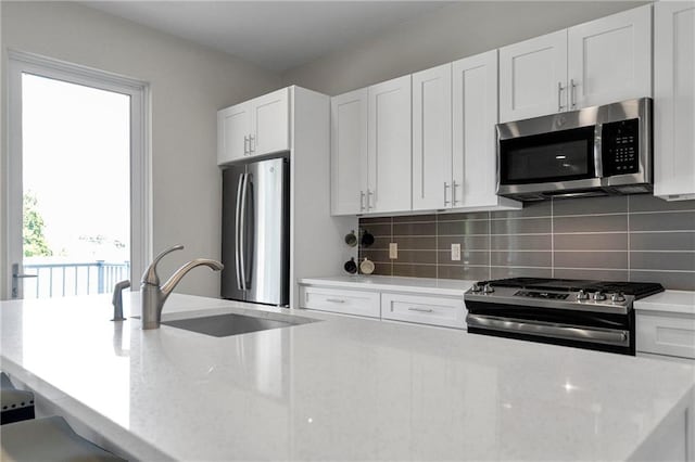 kitchen featuring a healthy amount of sunlight, appliances with stainless steel finishes, sink, and white cabinetry