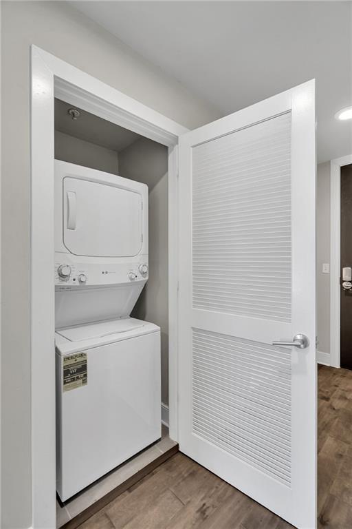 laundry area with hardwood / wood-style floors and stacked washer / drying machine