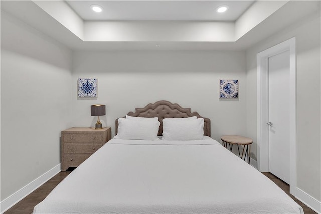 bedroom featuring a raised ceiling and dark hardwood / wood-style flooring