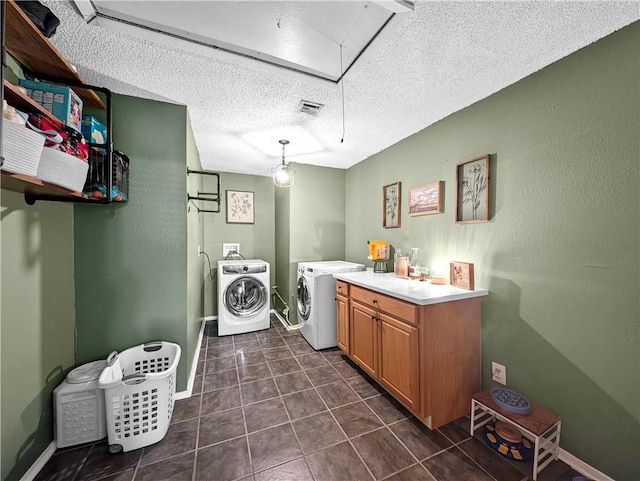 laundry area featuring a textured ceiling, dark tile patterned flooring, and independent washer and dryer