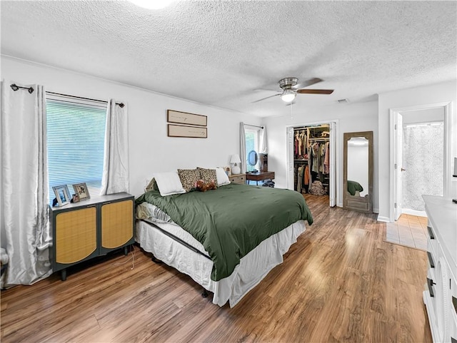 bedroom with ceiling fan, hardwood / wood-style floors, a closet, a spacious closet, and ensuite bathroom