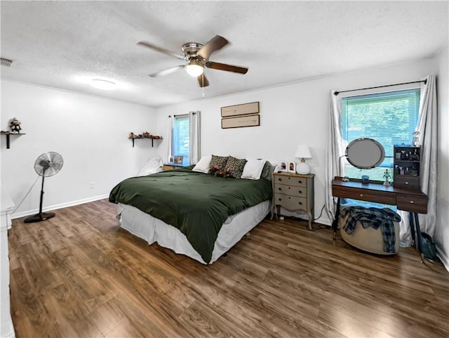 bedroom with a textured ceiling, dark hardwood / wood-style flooring, multiple windows, and ceiling fan