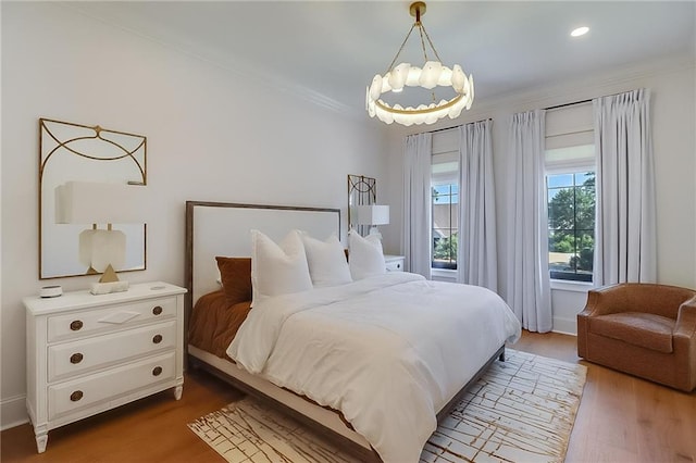 bedroom featuring ornamental molding, hardwood / wood-style flooring, and a notable chandelier