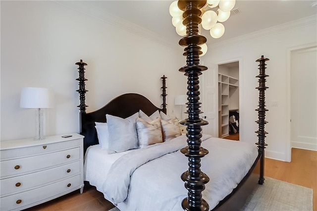 bedroom with a spacious closet, a closet, crown molding, and dark hardwood / wood-style flooring