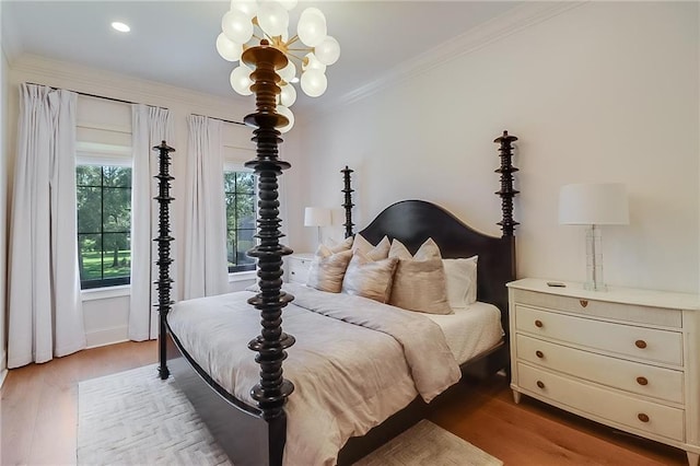 bedroom with ornamental molding, a notable chandelier, and light hardwood / wood-style floors